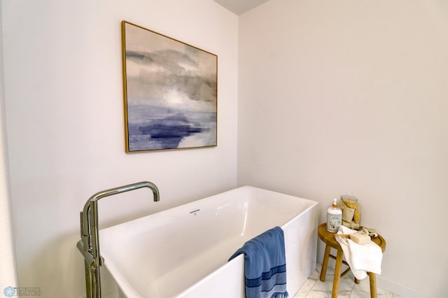 bathroom with a soaking tub and marble finish flooring