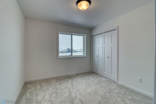unfurnished bedroom featuring carpet floors, baseboards, and a closet