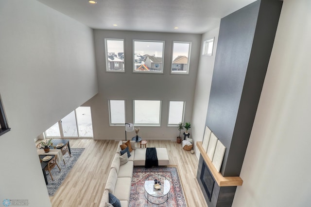 living room featuring wood finished floors, a high ceiling, recessed lighting, and baseboards