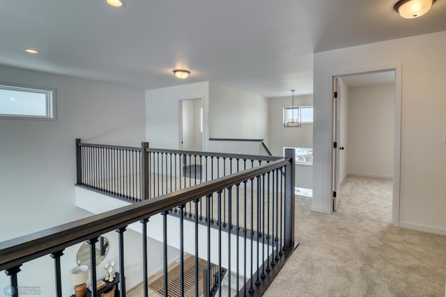 hall with an upstairs landing, light carpet, baseboards, a chandelier, and recessed lighting