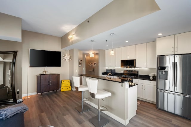 kitchen featuring appliances with stainless steel finishes, dark countertops, dark wood-style flooring, white cabinets, and recessed lighting