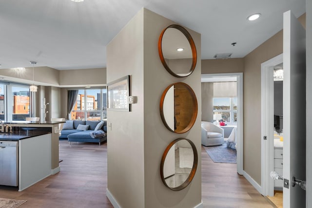 corridor with light wood-style flooring, healthy amount of natural light, recessed lighting, and baseboards