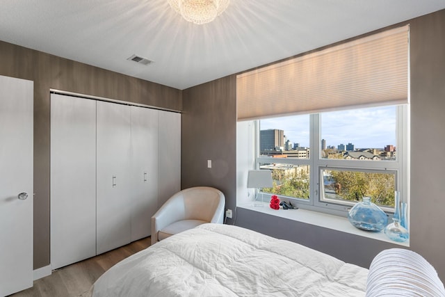 bedroom with wood finished floors, a city view, and a closet