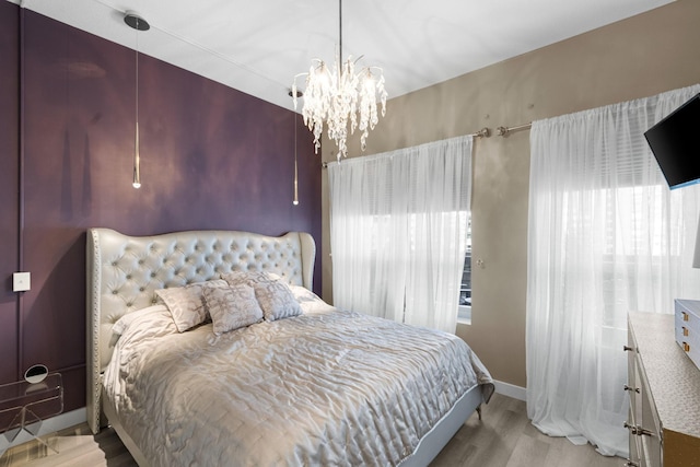 bedroom with wood finished floors, a chandelier, and baseboards