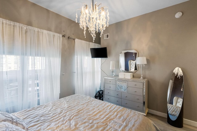 bedroom featuring wood finished floors, multiple windows, a chandelier, and baseboards