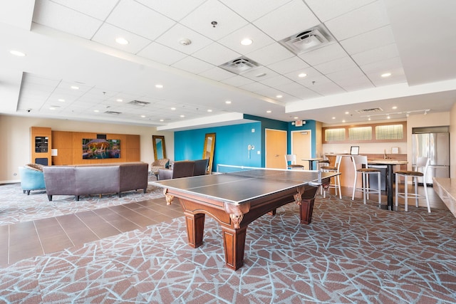 recreation room featuring a paneled ceiling and a raised ceiling