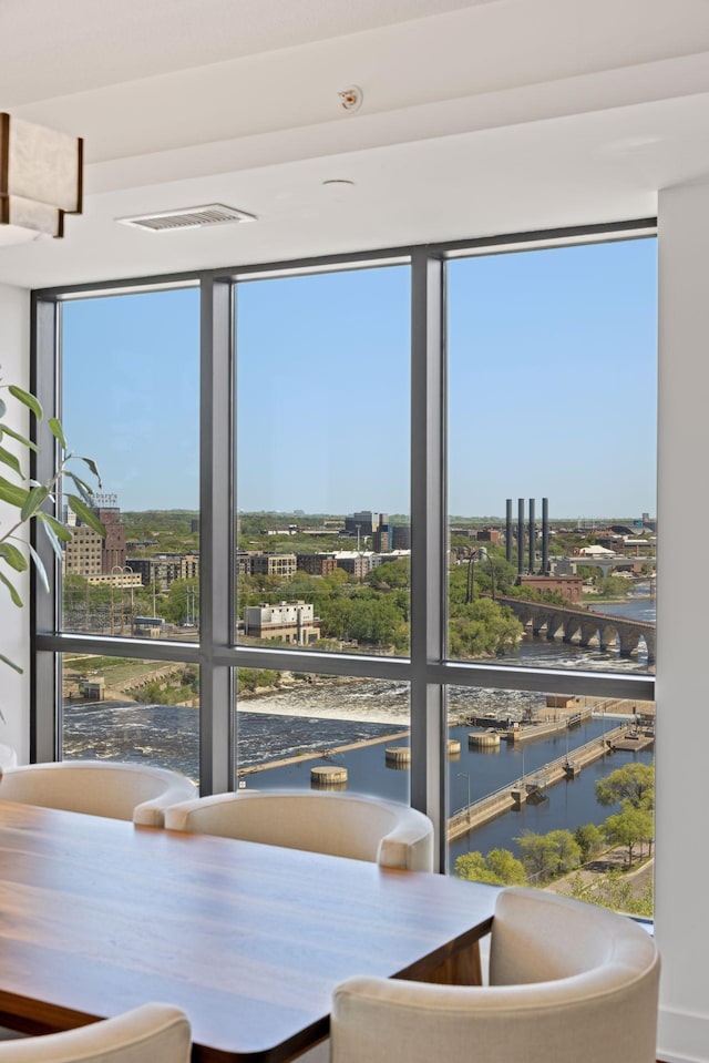 dining room with a city view, healthy amount of natural light, a wall of windows, and a water view