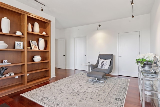 living area featuring dark wood finished floors, track lighting, and built in features