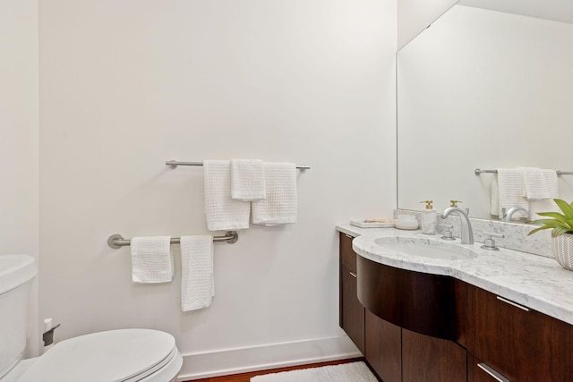 bathroom with toilet, vanity, and baseboards
