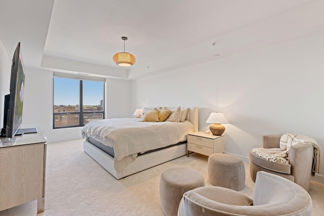 bedroom with light carpet and a tray ceiling