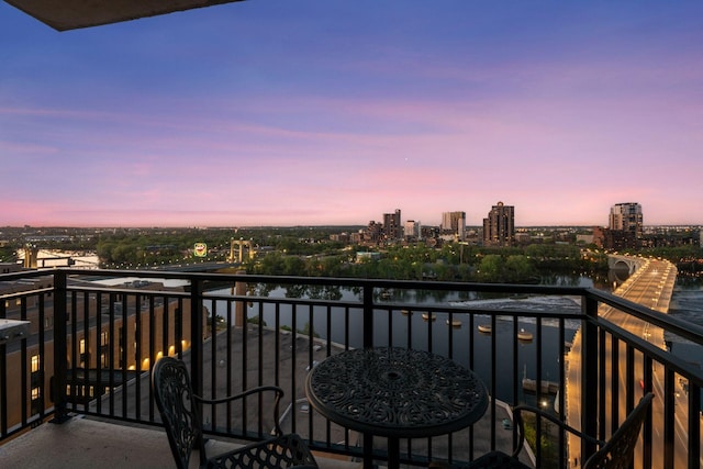 balcony at dusk featuring a view of city and a water view