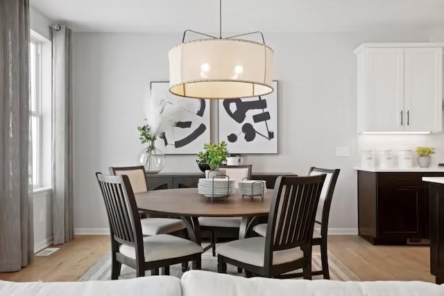 dining room with light wood-style floors, healthy amount of natural light, and baseboards