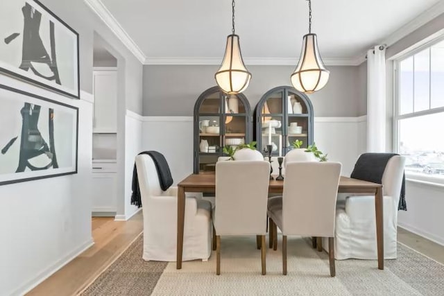 dining space featuring light wood-style flooring and crown molding