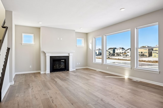 7197 Large Ave NE, Otsego, MN 55301 - unfurnished living room with stairs, a glass covered fireplace, healthy amount of natural light, wood finished floors, and recessed lighting