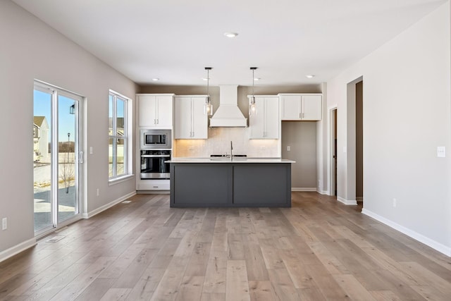 7197 Large Ave NE, Otsego, MN 55301 - kitchen with custom range hood, appliances with stainless steel finishes, white cabinets, light countertops, and a center island with sink