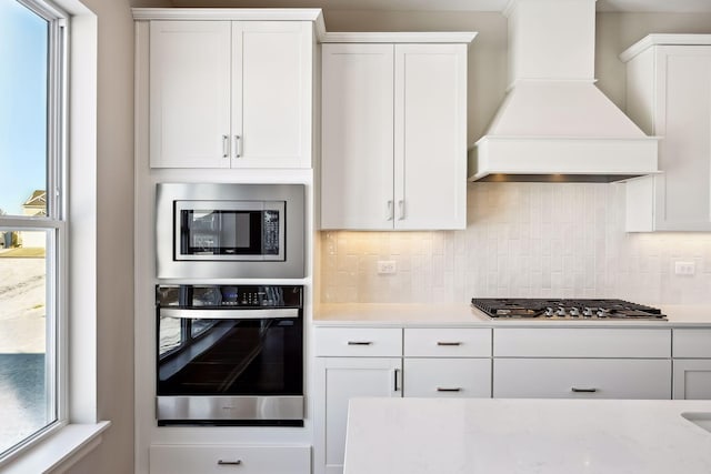 7197 Large Ave NE, Otsego, MN 55301 - kitchen with stainless steel appliances, custom exhaust hood, light countertops, tasteful backsplash, and white cabinets