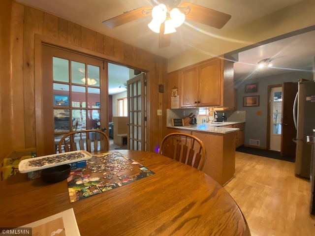 2828 Matilda St, Roseville, MN 55113 - dining room with a ceiling fan, light wood-style flooring, and wooden walls