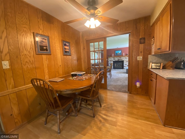 2828 Matilda St, Roseville, MN 55113 - dining space featuring a ceiling fan, a fireplace, light wood finished floors, and wood walls