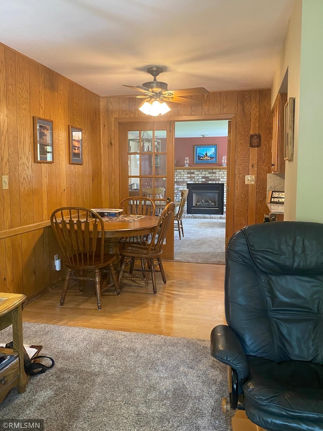 2828 Matilda St, Roseville, MN 55113 - dining area featuring wood walls, a tiled fireplace, a ceiling fan, and wood finished floors