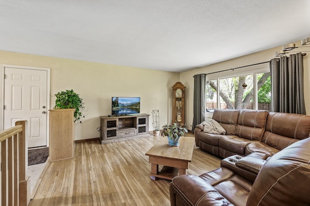 living room featuring light wood-type flooring, baseboards, and a textured ceiling