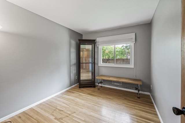 unfurnished room with wood finished floors, baseboards, and a baseboard heating unit