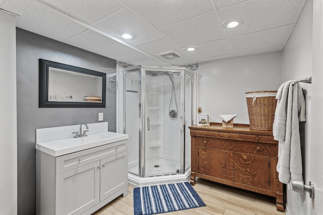 bathroom with vanity, a shower stall, wood finished floors, recessed lighting, and a paneled ceiling