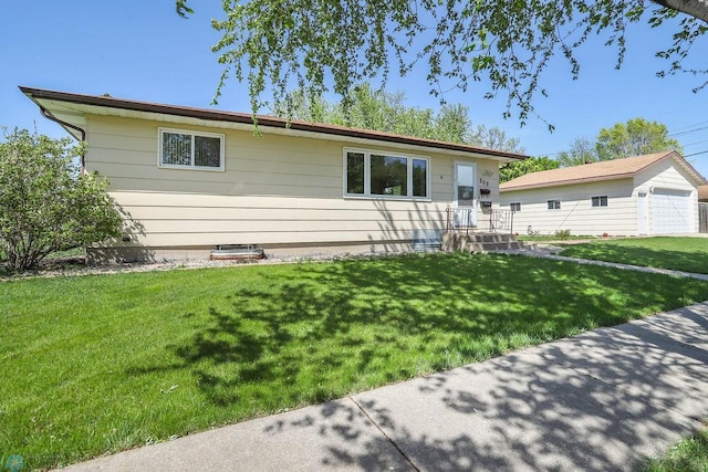 view of front of home featuring a front yard, a detached garage, and an outdoor structure