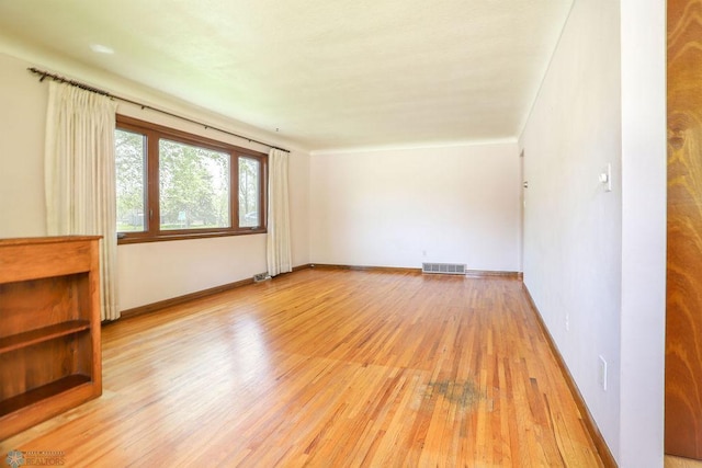 empty room featuring light wood finished floors and baseboards