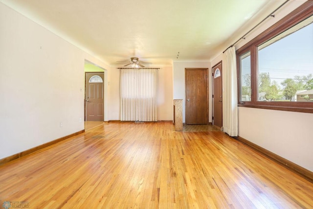 empty room featuring light wood-style flooring, baseboards, and ceiling fan