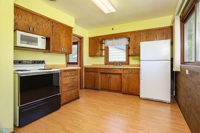 kitchen with white appliances, brown cabinets, light wood finished floors, and light countertops