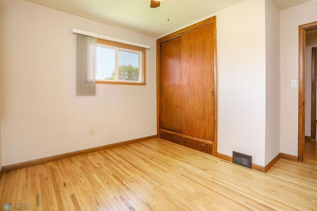 unfurnished bedroom with a closet, light wood-style floors, baseboards, and a ceiling fan