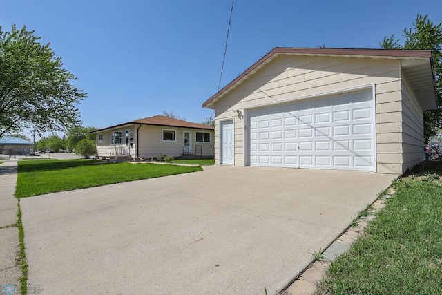 view of front of house with a detached garage, a front lawn, and an outbuilding