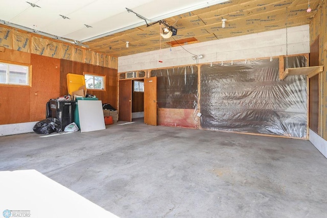 garage featuring a garage door opener and wooden walls