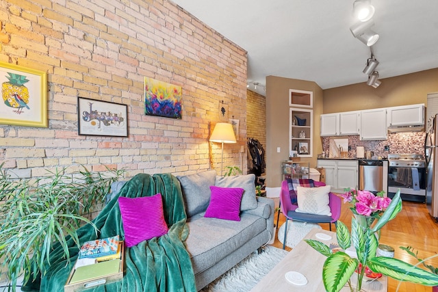 living area with light wood finished floors and brick wall