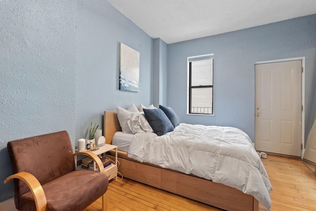bedroom with a textured wall and light wood-type flooring