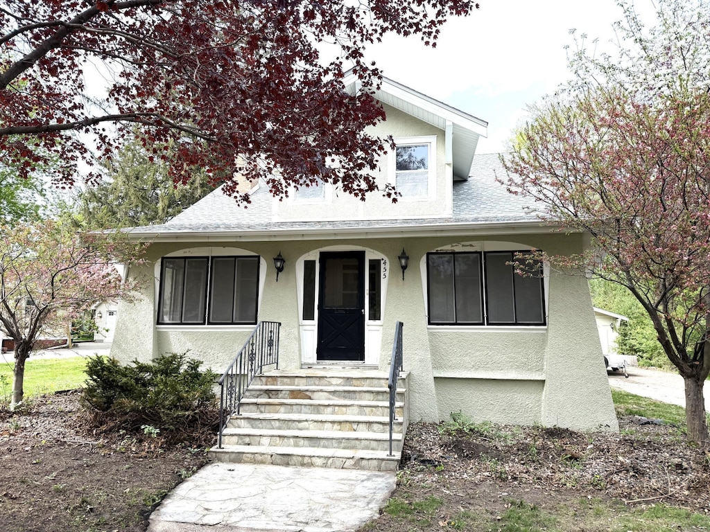 bungalow-style house featuring stucco siding, a porch, and a shingled roof