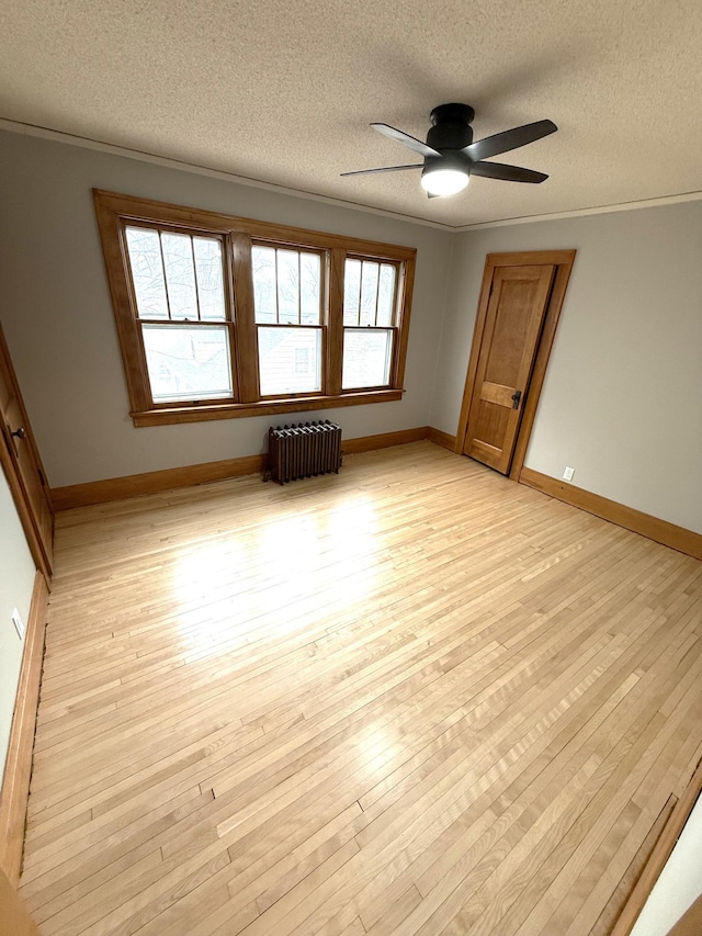 455 3rd St SE, Cokato, MN 55321 - unfurnished room featuring radiator, a textured ceiling, light wood finished floors, a ceiling fan, and crown molding