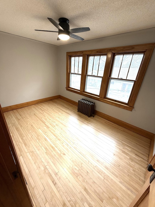 455 3rd St SE, Cokato, MN 55321 - unfurnished room with radiator heating unit, plenty of natural light, a textured ceiling, a ceiling fan, and light wood finished floors