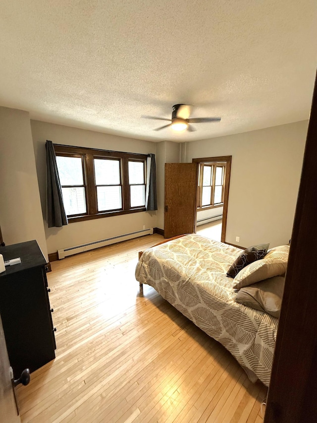 455 3rd St SE, Cokato, MN 55321 - bedroom featuring a baseboard heating unit, a textured ceiling, light wood finished floors, and a ceiling fan