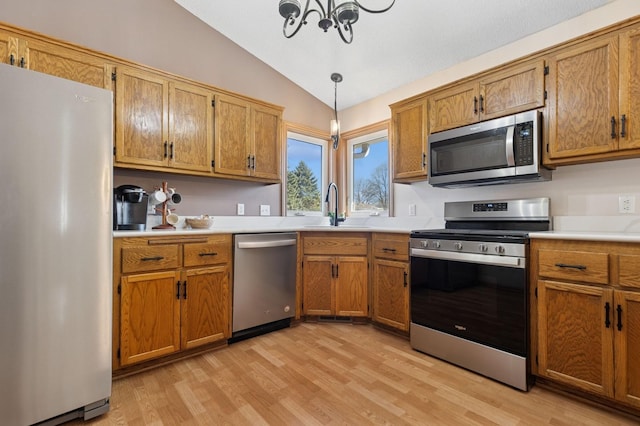 1284 Otter Ridge Rd, White Bear Twp, MN 55110 - kitchen featuring appliances with stainless steel finishes, lofted ceiling, light wood finished floors, a sink, and brown cabinetry