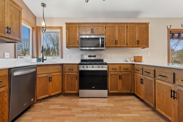 1284 Otter Ridge Rd, White Bear Twp, MN 55110 - kitchen featuring appliances with stainless steel finishes, a sink, light wood finished floors, and brown cabinets