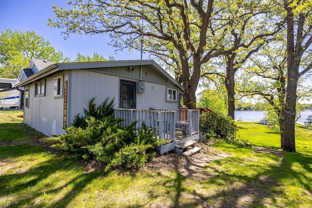 view of property exterior with a deck with water view and a lawn