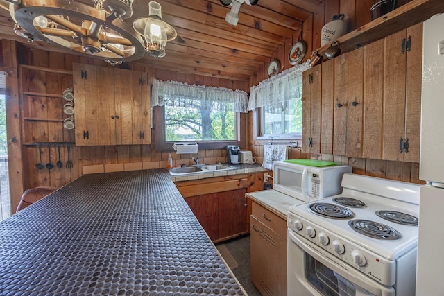 kitchen featuring white appliances, a sink, tile counters, brown cabinetry, and a chandelier