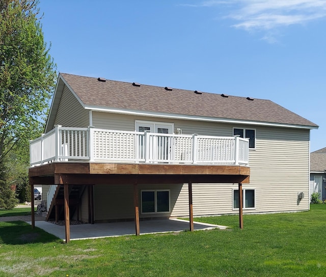 rear view of house featuring a patio area, a deck, a lawn, and a shingled roof