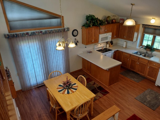 kitchen featuring white appliances, a sink, dark wood-style floors, a peninsula, and lofted ceiling