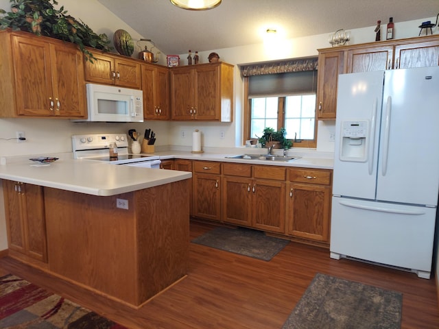 kitchen with white appliances, a sink, dark wood-type flooring, a peninsula, and lofted ceiling