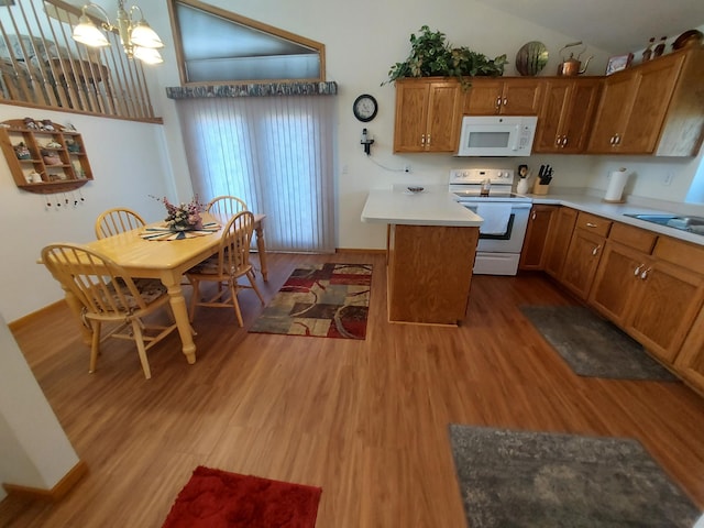 kitchen with white appliances, wood finished floors, a chandelier, brown cabinets, and vaulted ceiling