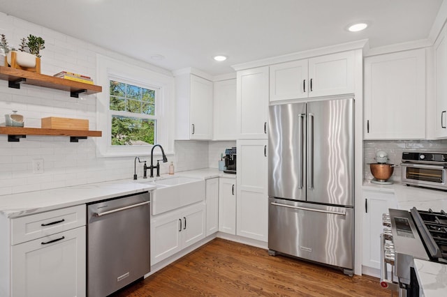 kitchen with stainless steel appliances, a sink, backsplash, white cabinets, and recessed lighting