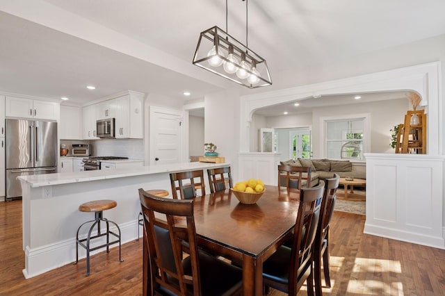 dining area featuring recessed lighting, dark wood finished floors, and arched walkways