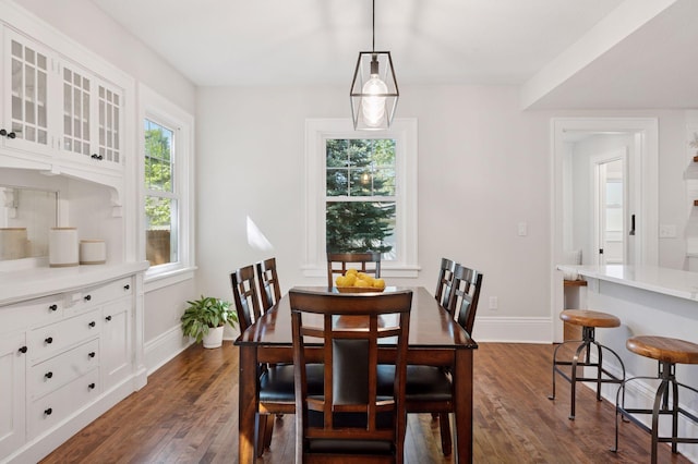 dining space featuring dark wood-type flooring and baseboards